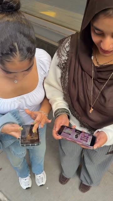 Two Baruch CEO members looking at their phones